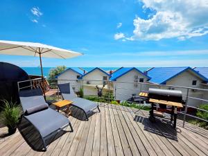 a deck with chairs and a grill and an umbrella at Великі котеджі з терасами у моря Совіньйон in Odesa