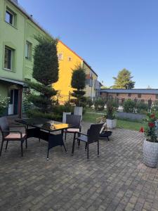 a patio with a table and chairs and a yellow building at Apartments Zur Eiche in Großräschen +6 photos