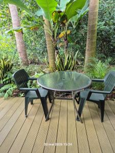a glass table and two chairs on a deck at La familiale in Salazie