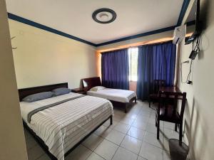 a bedroom with two beds and a desk and a window at Alojamiento 22 dé octubre in Santa Cruz de la Sierra