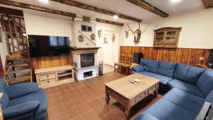a living room with a blue couch and a tv at Chata Kopánka in Moderštôlňa