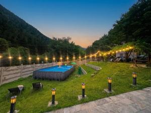 a yard with a swimming pool in the grass with lights at Serenity Likani Villa Hotel in Borjomi +51 photos