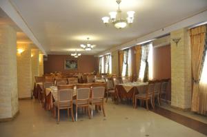 ein Esszimmer mit Tischen, Stühlen und einem Kronleuchter in der Unterkunft Avtoport Restorant Hotel Complex in Winnyzja