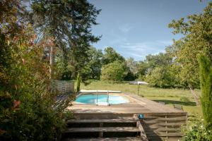 a swimming pool on a wooden deck in a garden at Chambres d’hôtes La Joyeuse in Préveranges