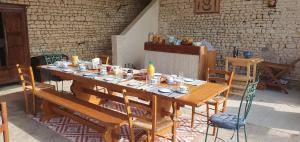 a long wooden table with chairs in a room at Les Fleurs de La Brise in Nueil-sous-Faye
