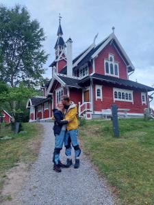 a man hugging a man in front of a red house at Tusenvik in Høybukt