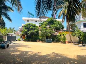 a large yard with trees and a building at Akkaraipattu Guest House in Akkaraipattu