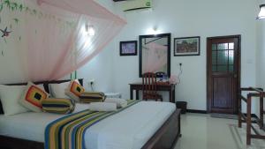 a bedroom with a bed with two chairs in it at Winmi Resort in Habarana