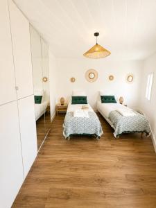 two beds in a bedroom with white walls and wood floors at Résidence de la Place in Pont-du-Château