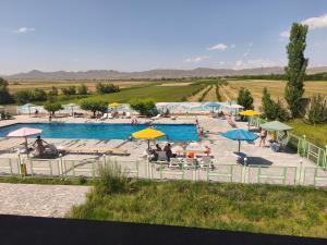 a pool with umbrellas and people sitting on the beach at Erazank Hotel in Gyumri