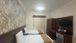 a hotel room with two beds and a tv at براديس لاند نبراس الهدئ in Mecca