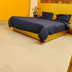a bedroom with a bed with blue sheets and a yellow wall at Gurudeva stay inn in Covelong