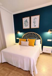 a bedroom with a large white bed with yellow pillows at Casa Girasoles terraza patio aire acondicionado in Corralejo