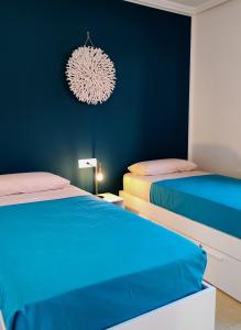a bedroom with two beds and a blue wall at Casa Girasoles terraza patio aire acondicionado in Corralejo