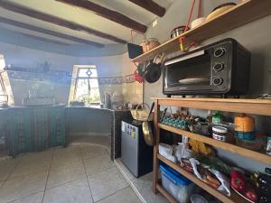 a kitchen with a microwave on a shelf at Cosy Private Room In A Community Home - A Space To Remember You In Andean Mountains in Pisac