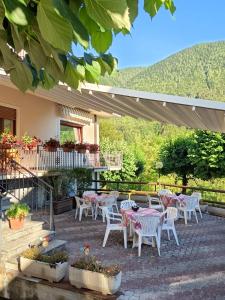 a patio with white tables and chairs and a mountain at Albergo Bellavista in Re