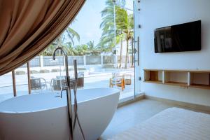 a bathroom with a tub and a tv and a balcony at Atlantic Shores Resort in Igbolobi