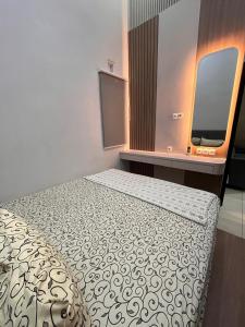 a small bedroom with a bed and a tv at Emmir Homestay in Cilacap