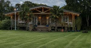 a log cabin with palm trees in front of a yard at Scarthingmoor Lodges in Weston