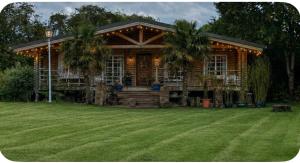 a log cabin with palm trees in front of a yard at Scarthingmoor Lodges in Weston