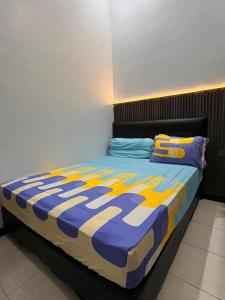 a bedroom with a bed with a blue and yellow comforter at Emmir Homestay in Cilacap