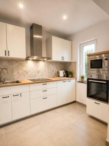 a kitchen with white cabinets and a microwave at Escale Tout Confort Maison entière Parking gratuit Proche Aéroport Charleroi in Charleroi
