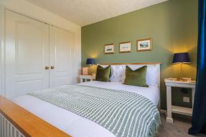a bedroom with a large white bed with green walls at Stylish Cheshire House in Winsford