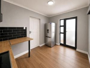 an empty kitchen with a stainless steel refrigerator at Pecan Tree Lodge in Cape Town