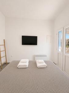 a white bedroom with a bed with two towels on it at Orama Suite II Mykonos Sunset & Pool in Mikonos