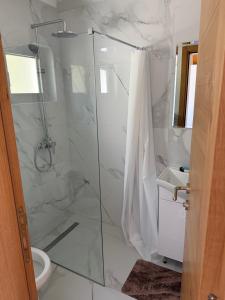 a white bathroom with a shower and a toilet at Bungalows Panorama Hills in Plužine