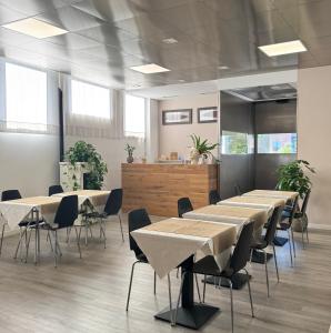 a row of tables and chairs in a room with windows at Hotel Angi in Fossò