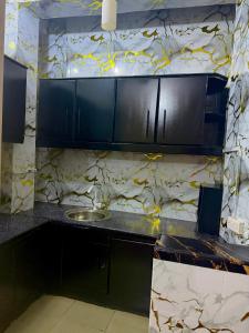 a kitchen with black cabinets and a sink at Alpha serenity in Mwanza