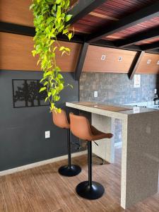 a kitchen with two bar stools and a counter at Chalé Aconchego in Caparaó Velho