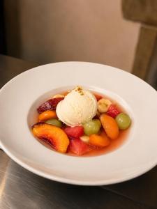 a bowl of fruit with an ice cream on a plate at Mas du pommier Gala in Gagnières