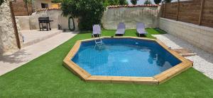 a swimming pool with two chairs on the grass at El rincon de Fausto in Mudrián