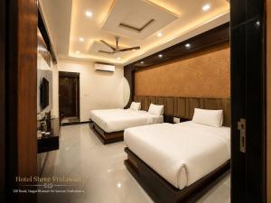 a bedroom with two beds and a tv at Hotel Shree Vrindavan in Nāthdwāra