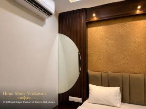 a bedroom with a bed and a gold wall at Hotel Shree Vrindavan in Nāthdwāra