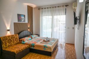a bedroom with a bed and a couch and a window at Apartman Amin&Amina in Ulcinj