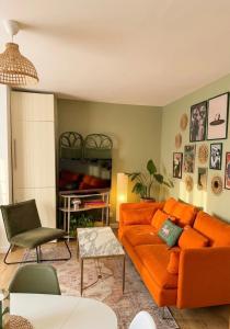 a living room with an orange couch and a tv at Au Canon - Parking gratuit - Bords de Loire in Orléans