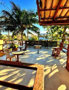 a patio with tables and chairs and palm trees at Beachfront suite right on the sand in Cabo Frio