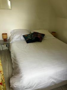 a white bed with a pillow on top of it at L'Ecrin Normand appartement avec jardin comportant 2 lits 2 places et 1 lit 1 place in Cambremer