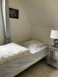 a bed with white sheets and a lamp on a table at L'Ecrin Normand appartement avec jardin comportant 2 lits 2 places et 1 lit 1 place in Cambremer +9 photos
