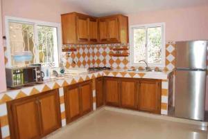 a kitchen with wooden cabinets and a stainless steel refrigerator at Villa Reine Saly in Saly Portudal