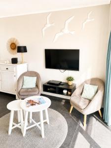 a living room with two chairs and a tv at De Zandkorrel - Amazing seaview in Wenduine