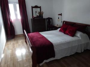 a bedroom with a bed with red pillows on it at Casa do Pinheiro in Louriceira