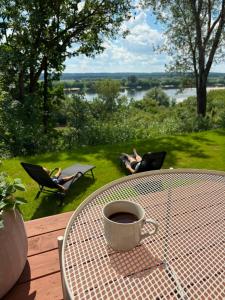a table with a cup of coffee and two people laying in chairs at PrzyStań w Ciszy in Kozielec