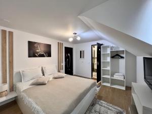 a white bedroom with a bed and a television at Casa Coltea in Moieciu de Jos