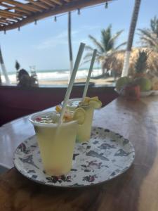 two drinks on a plate on a table with the beach at Karpatty Mar Cabañas in San Bernardo del Viento