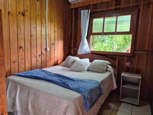 a bed in a wooden room with a window at Cabanas Areias in Praia do Rosa