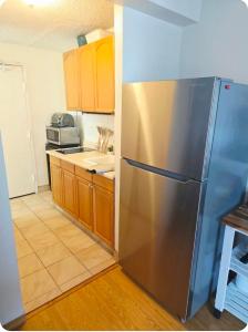 a kitchen with a stainless steel refrigerator and wooden cabinets at Waikiki Vacation Apartment in Honolulu